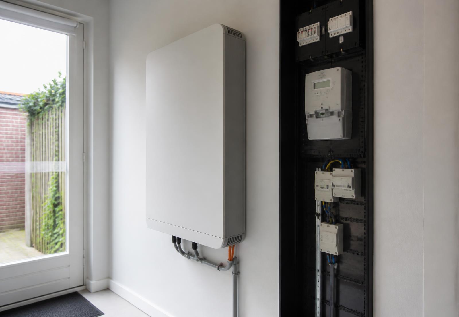 Thuisbatterij aan de muur naast een meterkast in een Nederlandse woning